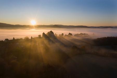 Curemonte backlit at sunrise in the mist, Correze, France